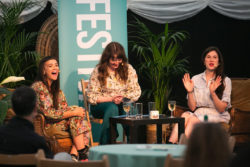 Three women sat around a table at The Bath Festival and laughing