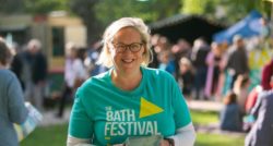 A volunteer wearing a The Bath Festival t-shirt posing for the camera and smiling